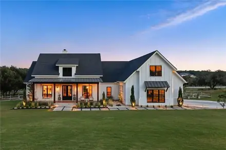 Farmhouse at dusk with a manicured natural grass lawn