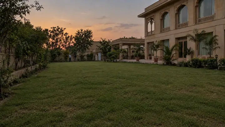 Well-kept natural grass lawn at sunset beside a stone building